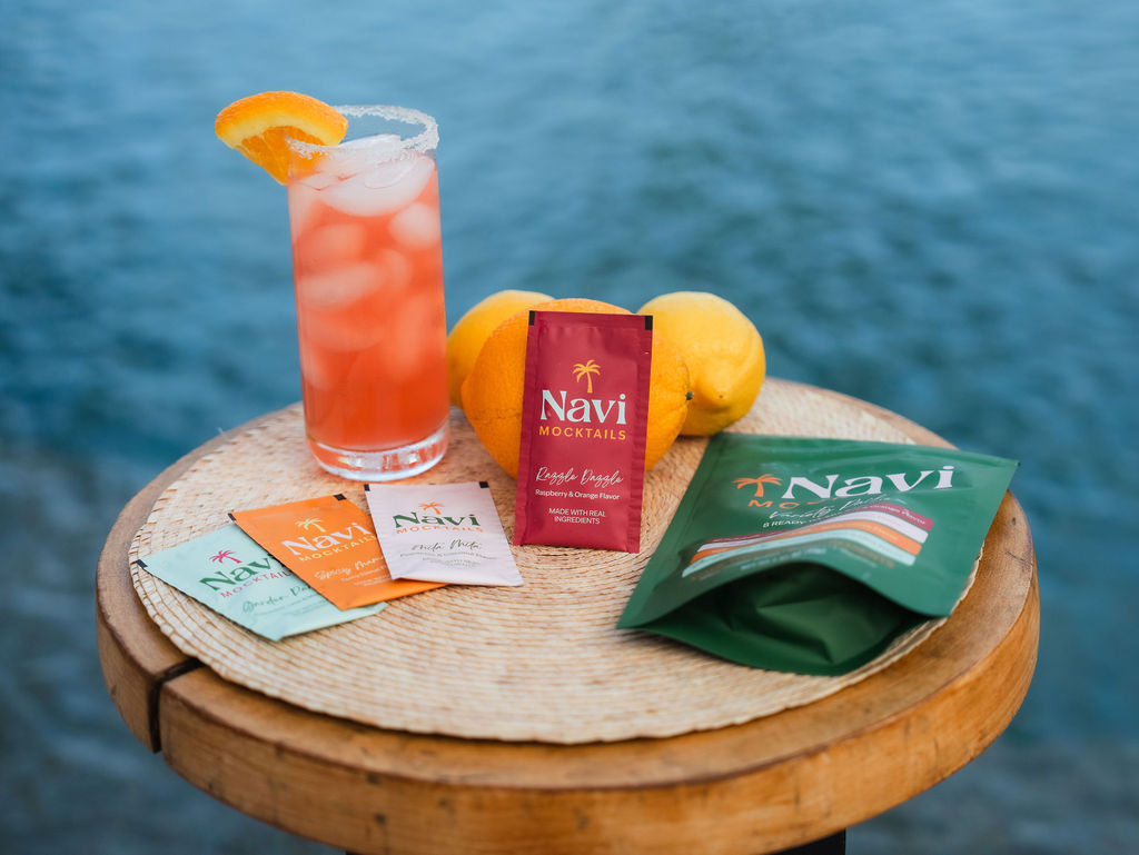Navi Mocktails packets and a finished mocktail by the water