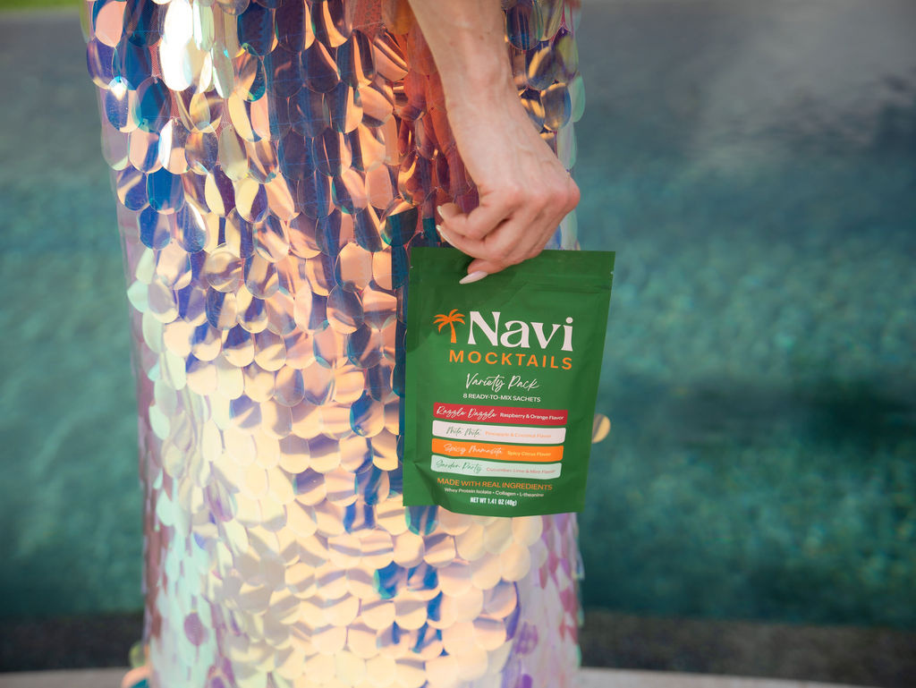 Hand holding a Navi Mocktails variety pack in a sequined dress